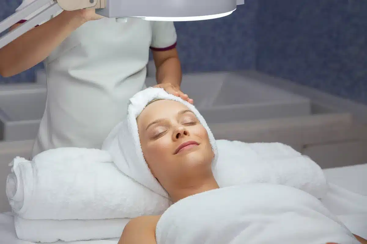 A woman relaxing on a treatment table in a serene massage room, considering facial spa options.