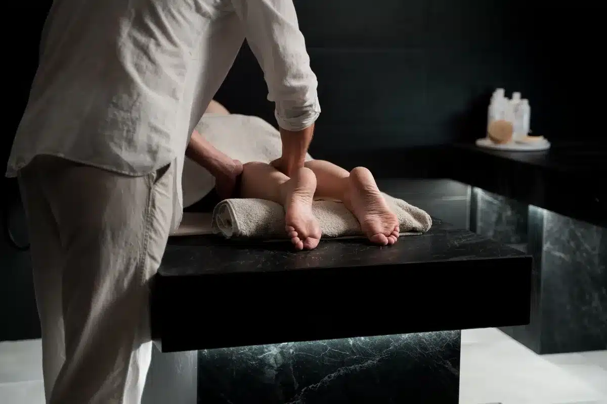 A therapist giving a calming foot massage in a modern spa, enhancing relaxation before a microcurrent facial.