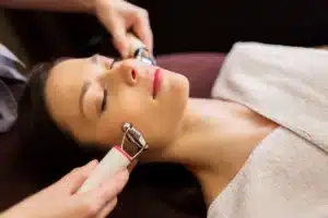 A young woman receives a microcurrent facial treatment at a spa, highlighting rejuvenating beauty technology.