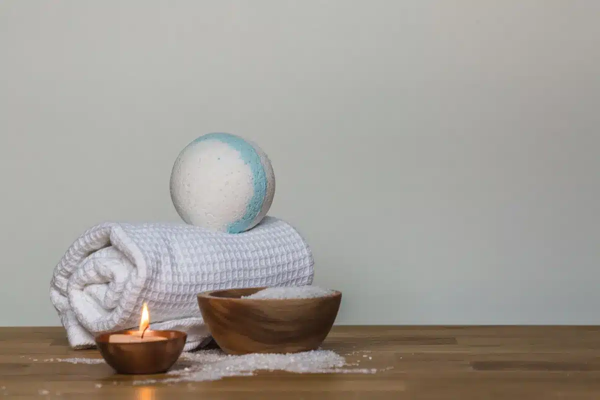 A tranquil spa scene featuring a bath bomb, salt, candle, and towel, ideal for relaxation during a facial spa visit.